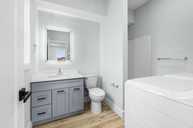 bathroom with washer and clothes dryer, vanity, toilet, and hardwood / wood-style flooring