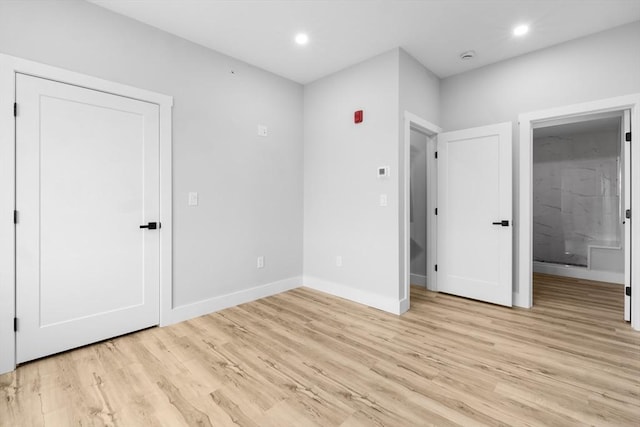 unfurnished bedroom featuring connected bathroom and light wood-type flooring