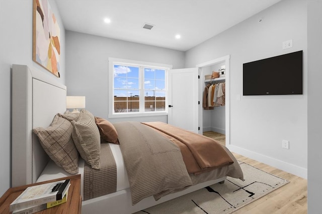 bedroom with a walk in closet, light wood-type flooring, and a closet