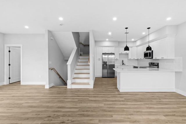 kitchen with decorative backsplash, kitchen peninsula, stainless steel appliances, pendant lighting, and white cabinetry