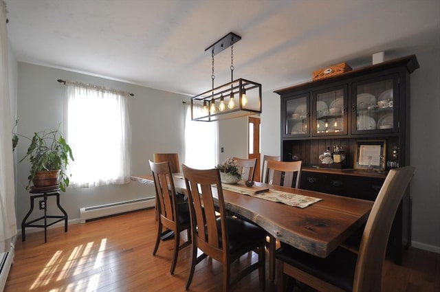 dining room with baseboards, a baseboard radiator, baseboard heating, and light wood-type flooring