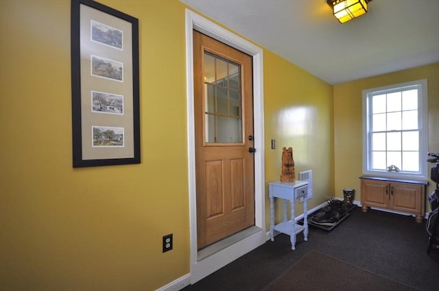 entryway with baseboards and dark carpet