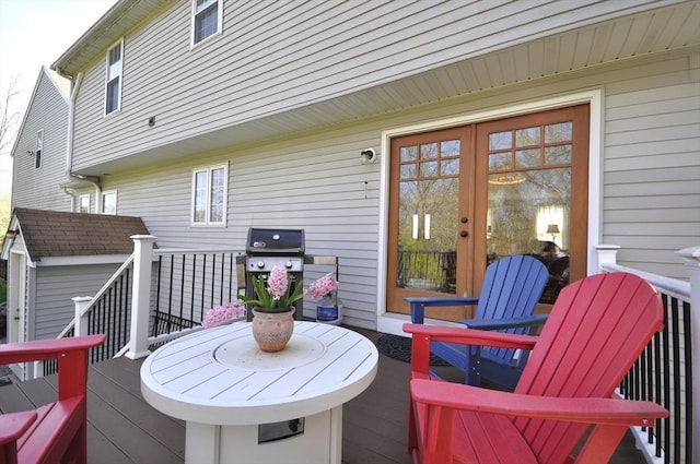 wooden terrace with an outdoor structure, a shed, french doors, and a grill