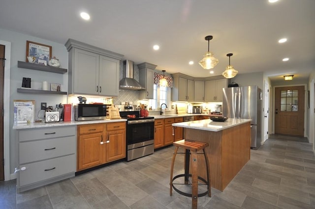 kitchen with wall chimney range hood, open shelves, appliances with stainless steel finishes, light countertops, and gray cabinets