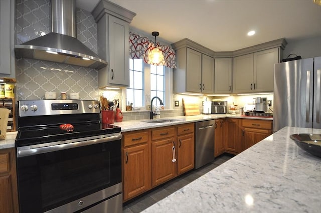 kitchen with light stone counters, a sink, wall chimney exhaust hood, stainless steel appliances, and backsplash