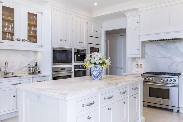 kitchen with high end range, a sink, white cabinetry, recessed lighting, and tasteful backsplash