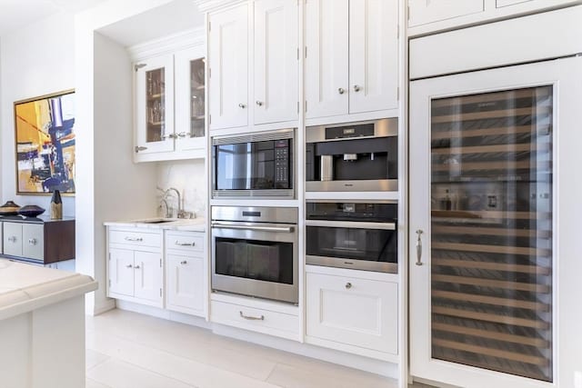 kitchen with stainless steel oven, wine cooler, black microwave, and white cabinets