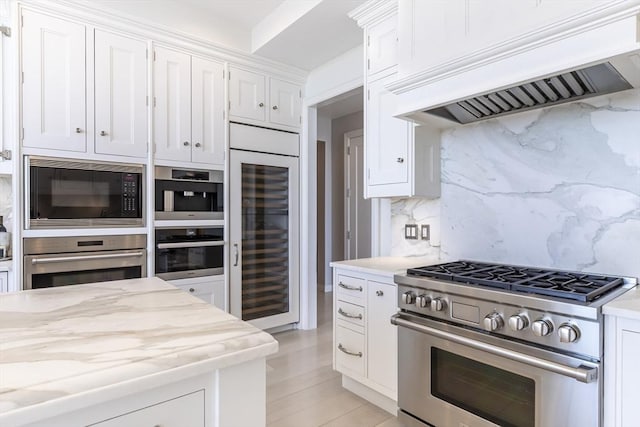 kitchen featuring stainless steel appliances, wine cooler, custom exhaust hood, tasteful backsplash, and white cabinetry