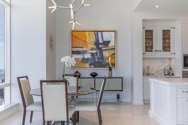 dining area featuring recessed lighting, baseboards, wet bar, a chandelier, and light wood-style floors