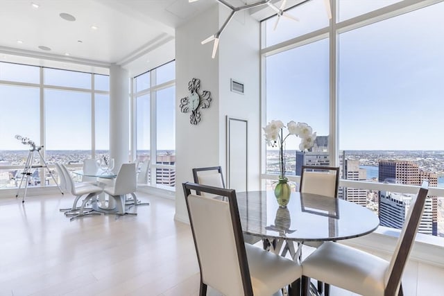 dining area featuring a wall of windows, healthy amount of natural light, wood finished floors, and a view of city