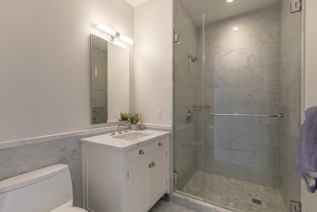 full bathroom with toilet, a stall shower, vanity, and wainscoting