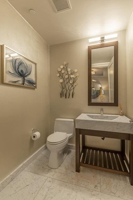 bathroom featuring toilet, marble finish floors, baseboards, and vanity