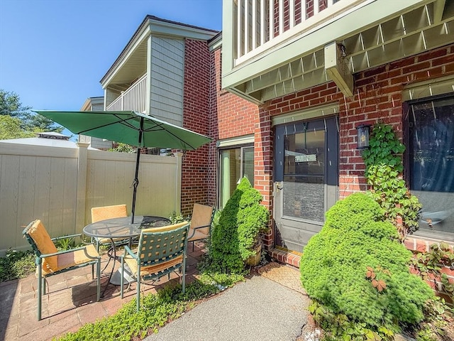 view of patio with fence, outdoor dining area, and a balcony