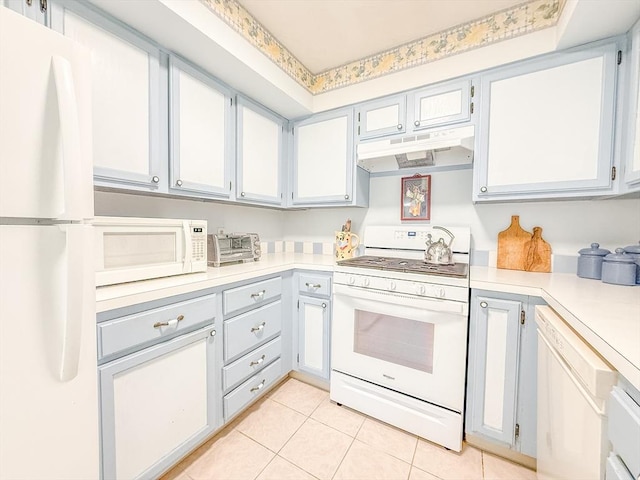 kitchen featuring white appliances, under cabinet range hood, light countertops, and light tile patterned floors