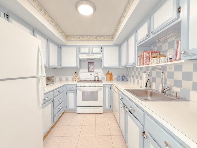 kitchen with white appliances, under cabinet range hood, a sink, light countertops, and light tile patterned flooring
