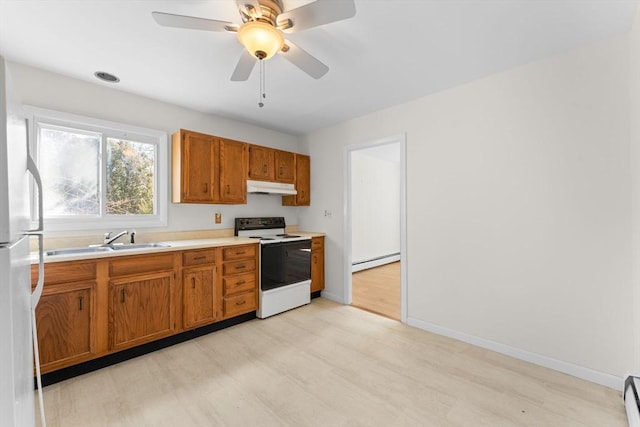 kitchen with electric stove, a sink, a baseboard heating unit, under cabinet range hood, and freestanding refrigerator