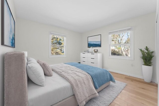 bedroom featuring light wood-style flooring, multiple windows, and baseboards