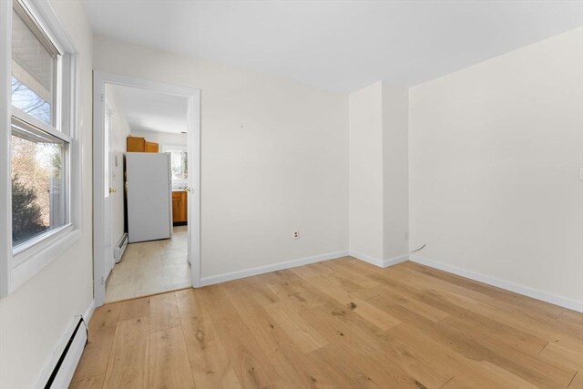 unfurnished room with light wood-type flooring, baseboards, and a baseboard radiator