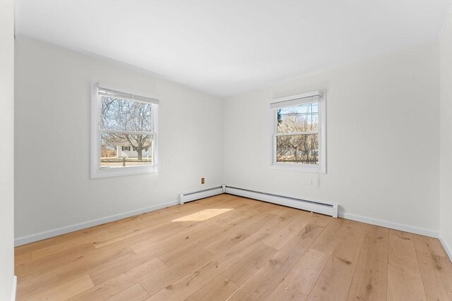 spare room with plenty of natural light, a baseboard radiator, baseboards, and hardwood / wood-style floors