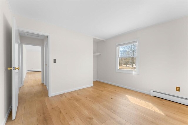 unfurnished bedroom featuring light wood-type flooring, baseboards, and a baseboard radiator