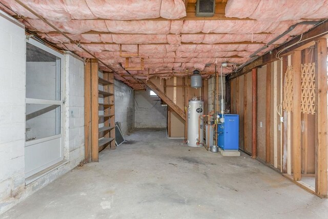 unfinished below grade area featuring water heater, visible vents, and a heating unit