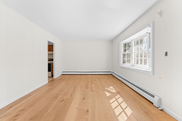 spare room with a baseboard heating unit, light wood-style floors, and baseboard heating