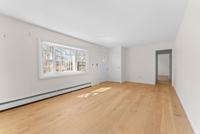 spare room featuring light wood finished floors, baseboards, and a baseboard radiator