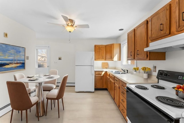 kitchen with brown cabinetry, freestanding refrigerator, under cabinet range hood, range with electric stovetop, and a baseboard heating unit