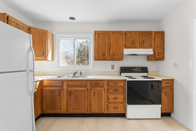 kitchen featuring brown cabinetry, electric range, freestanding refrigerator, a sink, and under cabinet range hood