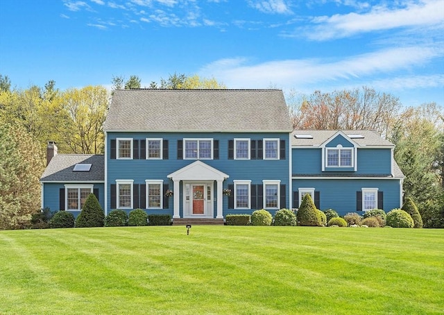 colonial house featuring a chimney and a front yard