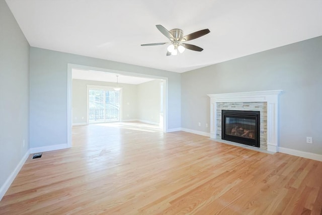 unfurnished living room featuring a tile fireplace, light wood-type flooring, and ceiling fan