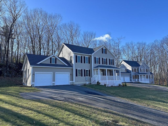 view of front of house with a garage, covered porch, and a front lawn