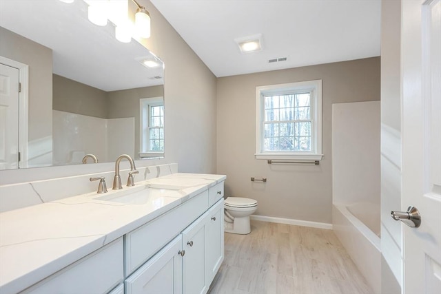 full bathroom featuring hardwood / wood-style flooring, vanity, toilet, and washtub / shower combination