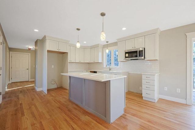 kitchen with pendant lighting, white cabinetry, a kitchen island, and plenty of natural light