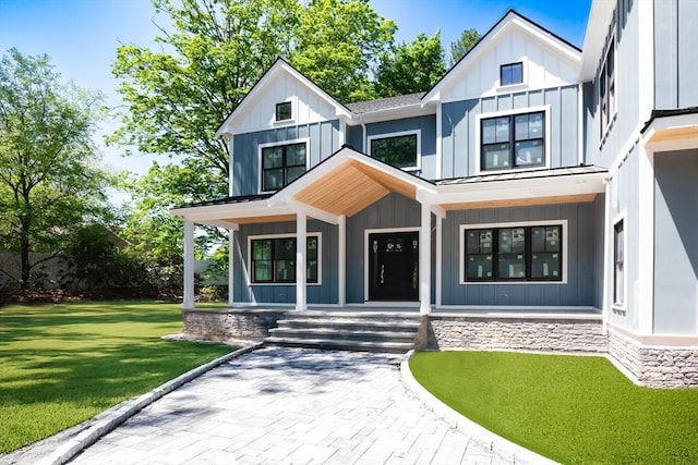 view of front facade featuring a porch, board and batten siding, a front lawn, a standing seam roof, and metal roof