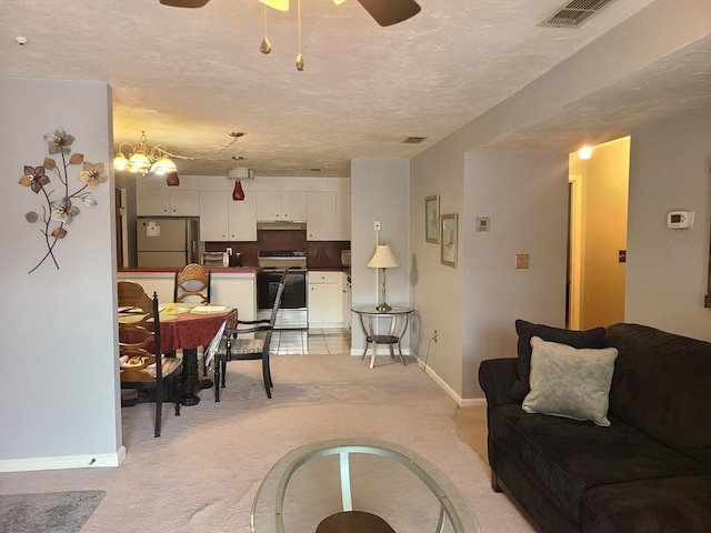 living area with visible vents, baseboards, light carpet, ceiling fan with notable chandelier, and a textured ceiling