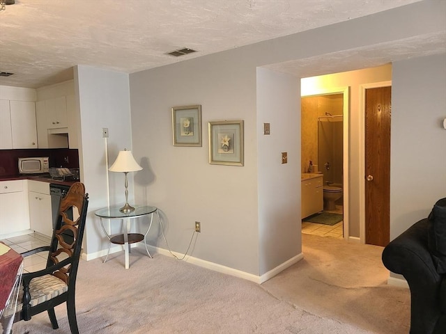 office area featuring a textured ceiling, baseboards, visible vents, and light carpet