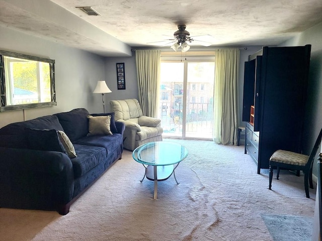 living room with carpet flooring, a ceiling fan, and visible vents