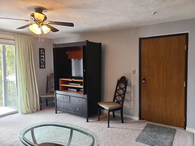 living area featuring light colored carpet, baseboards, and a textured ceiling