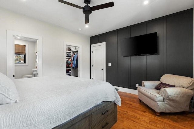 bedroom with ceiling fan, ensuite bathroom, light hardwood / wood-style flooring, a spacious closet, and a closet