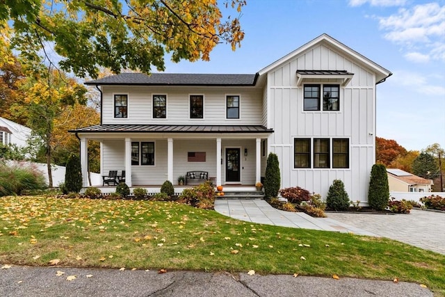 modern farmhouse featuring covered porch and a front yard