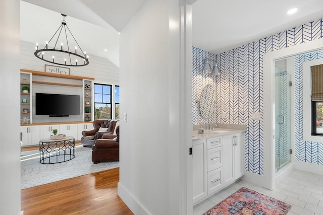 bathroom featuring hardwood / wood-style floors, vanity, a shower, a chandelier, and vaulted ceiling