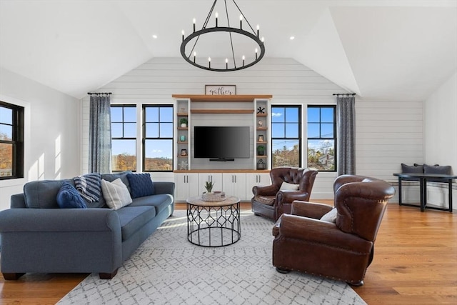 living room featuring a wealth of natural light, lofted ceiling, light hardwood / wood-style floors, and a chandelier