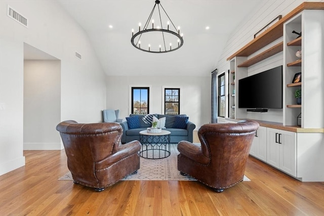 living room featuring light hardwood / wood-style flooring, a notable chandelier, and vaulted ceiling