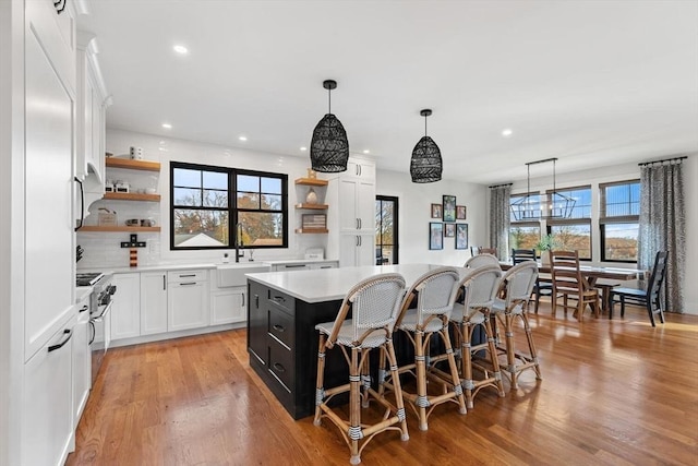 kitchen featuring light hardwood / wood-style floors, a center island, sink, white cabinetry, and hanging light fixtures