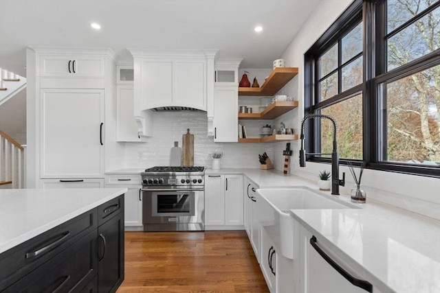 kitchen with decorative backsplash, white cabinetry, dark hardwood / wood-style floors, and high end stove