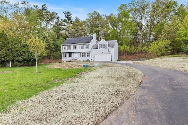 18 Candlewood Dr, Medway, MA 02053 - colonial-style house with asphalt driveway, solar panels, a front yard, and a chimney