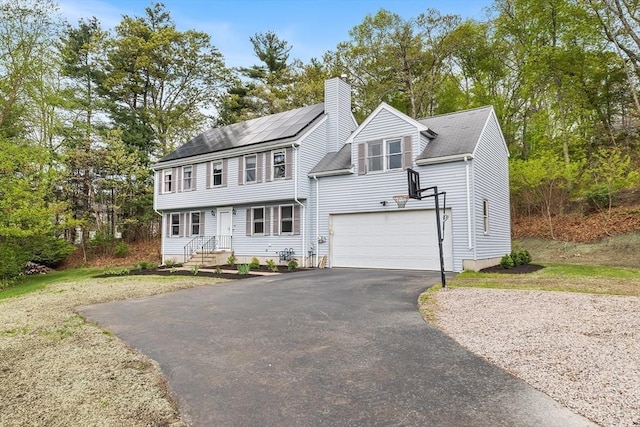 18 Candlewood Dr, Medway, MA 02053 - colonial house with asphalt driveway, a chimney, an attached garage, and roof mounted solar panels
