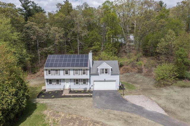 18 Candlewood Dr, Medway, MA 02053 - view of front of home with asphalt driveway, a wooded view, solar panels, an attached garage, and a chimney