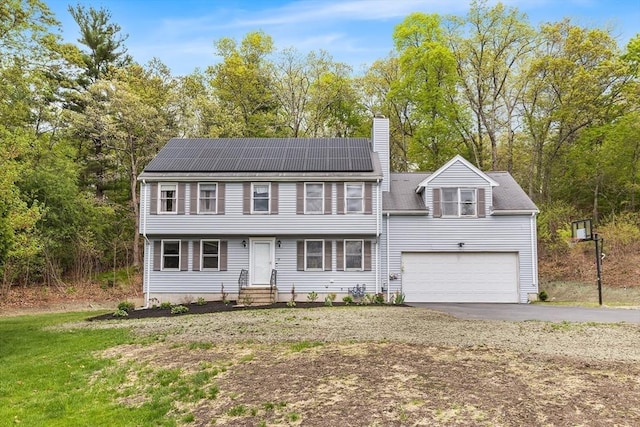 18 Candlewood Dr, Medway, MA 02053 - colonial home featuring asphalt driveway, a chimney, roof mounted solar panels, an attached garage, and entry steps